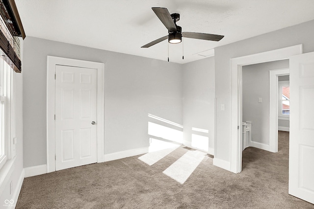 carpeted spare room featuring ceiling fan and baseboards