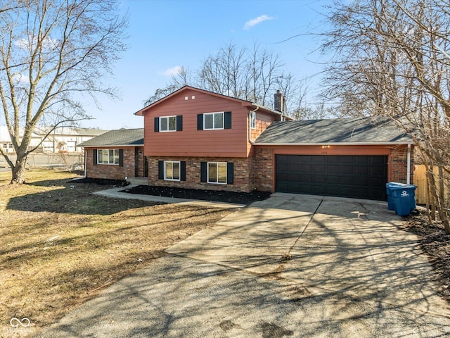 split level home featuring an attached garage, brick siding, fence, concrete driveway, and a chimney