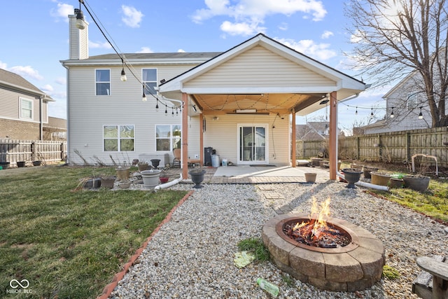 rear view of house featuring a yard, a chimney, an outdoor fire pit, a patio area, and a fenced backyard