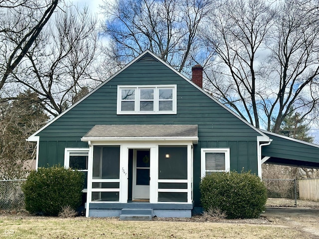 bungalow featuring board and batten siding, a sunroom, and fence