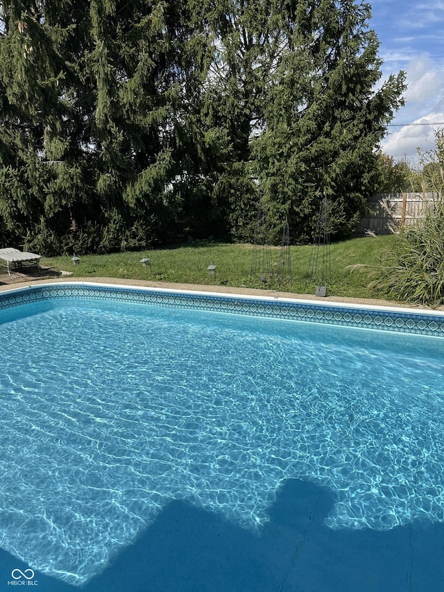 pool featuring a lawn and fence