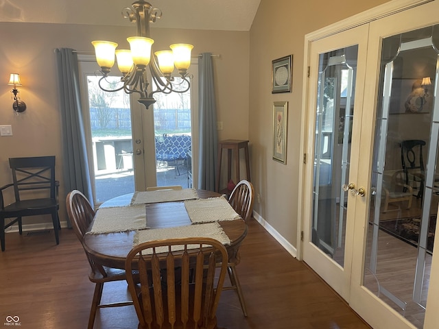 dining space featuring baseboards, a chandelier, lofted ceiling, french doors, and dark wood-style floors