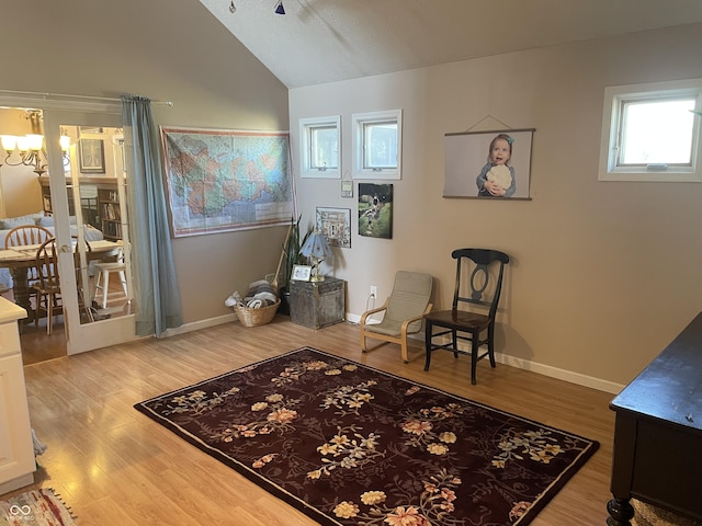 sitting room featuring baseboards, ceiling fan with notable chandelier, vaulted ceiling, and light wood finished floors