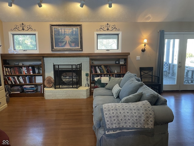 living area featuring a wealth of natural light, a fireplace, a textured ceiling, and wood finished floors