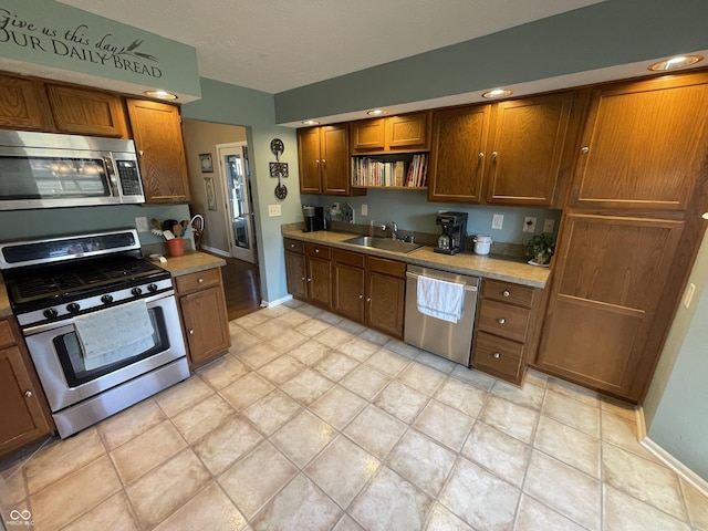 kitchen with open shelves, a sink, light countertops, appliances with stainless steel finishes, and brown cabinets