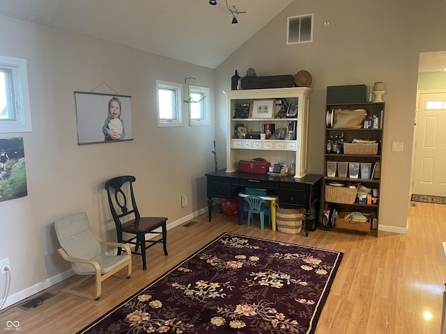 living area with visible vents, baseboards, lofted ceiling, and wood finished floors