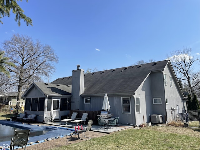 back of house featuring fence, roof with shingles, a yard, a sunroom, and a patio area