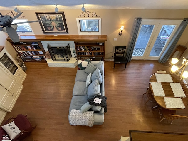 living room featuring french doors, baseboards, wood finished floors, and a fireplace