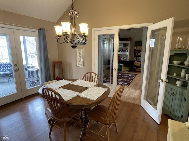 dining room featuring dark wood-type flooring, a notable chandelier, french doors, and lofted ceiling