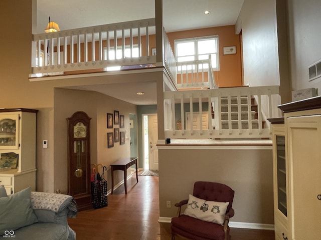 living area featuring stairway, wood finished floors, baseboards, recessed lighting, and a towering ceiling