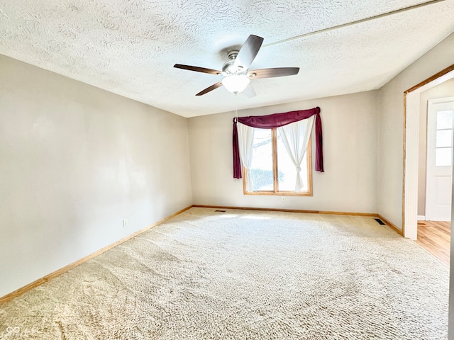 spare room featuring a ceiling fan, light colored carpet, visible vents, and baseboards