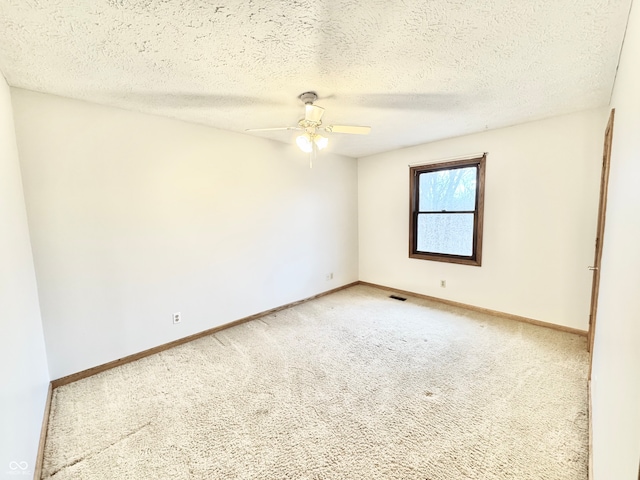 empty room featuring light carpet, baseboards, visible vents, a ceiling fan, and a textured ceiling