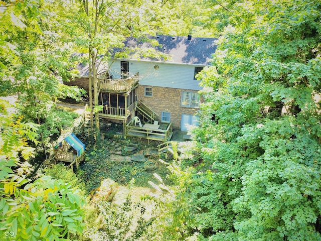 rear view of property with stairway, a wooden deck, and a sunroom