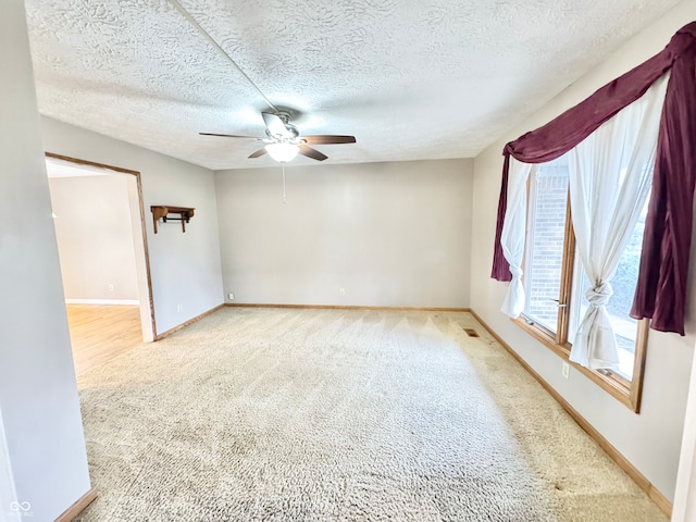 carpeted empty room featuring ceiling fan, baseboards, and a textured ceiling