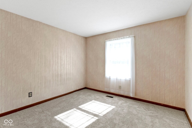 carpeted spare room featuring visible vents and baseboards