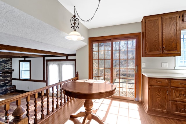 dining room featuring a textured ceiling, light wood finished floors, and beamed ceiling