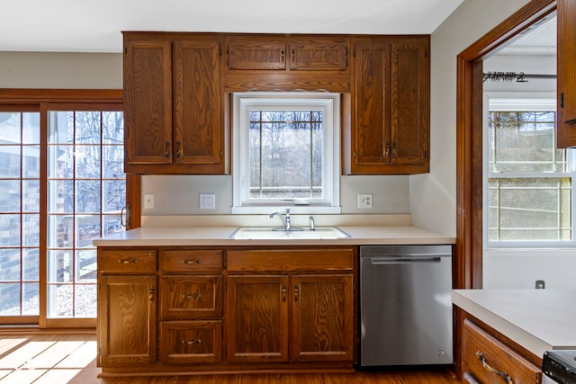 kitchen with dishwasher, light countertops, a sink, and a healthy amount of sunlight