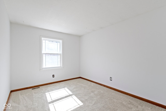 carpeted spare room featuring visible vents and baseboards