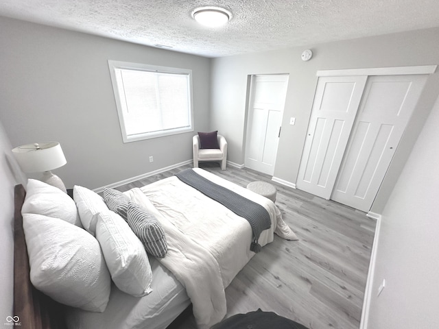 bedroom featuring light wood-style flooring, a closet, baseboards, and a textured ceiling