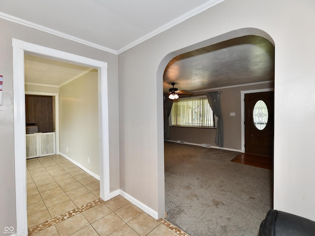 tiled entrance foyer with baseboards, arched walkways, ceiling fan, ornamental molding, and carpet