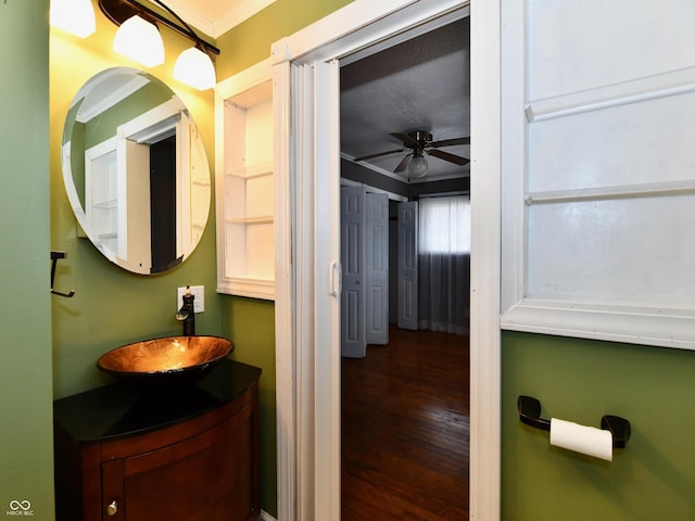 bathroom with crown molding, ceiling fan, vanity, and wood finished floors