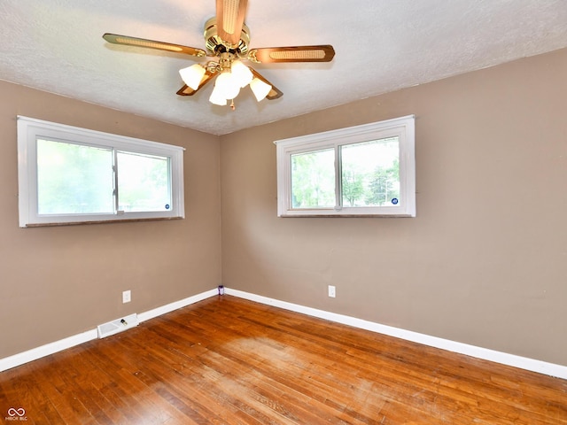 unfurnished room featuring a healthy amount of sunlight, wood-type flooring, and baseboards