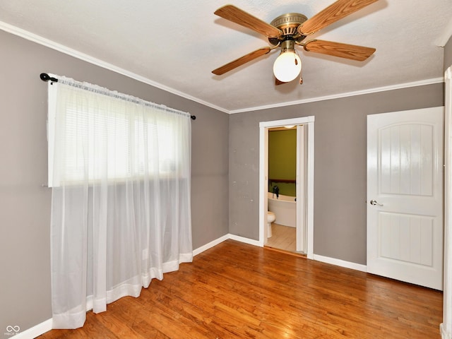 unfurnished room featuring baseboards, wood finished floors, a ceiling fan, and crown molding