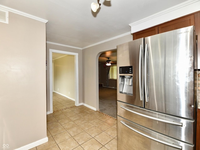 kitchen featuring light tile patterned floors, stainless steel fridge, arched walkways, and crown molding