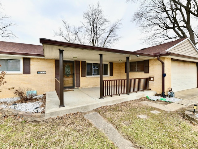 ranch-style home featuring brick siding, a shingled roof, covered porch, an attached garage, and driveway