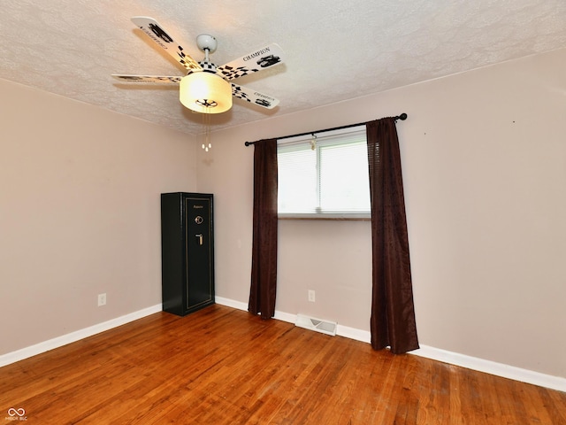 spare room featuring a textured ceiling, wood finished floors, visible vents, and baseboards