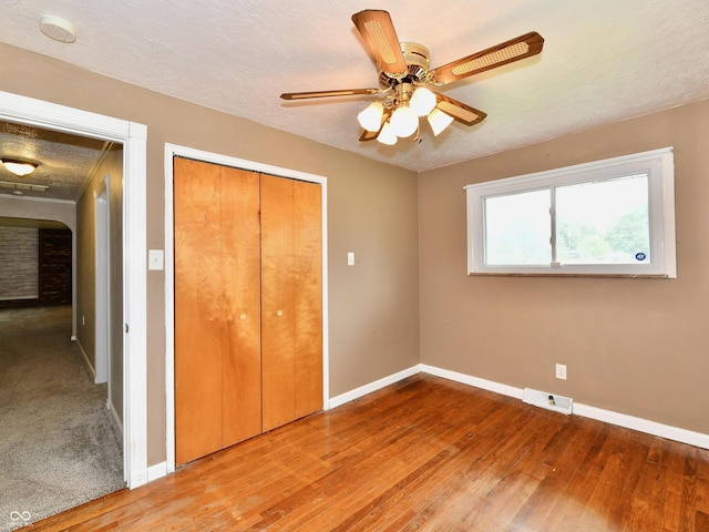 unfurnished bedroom featuring a closet, visible vents, a textured ceiling, and wood finished floors