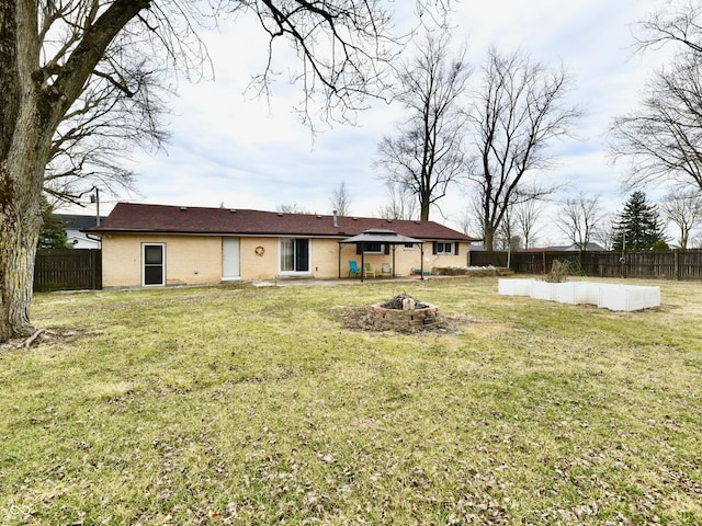 back of property featuring an outdoor fire pit, a lawn, and a fenced backyard