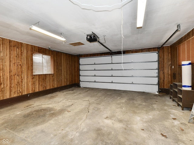 garage with wood walls and a garage door opener