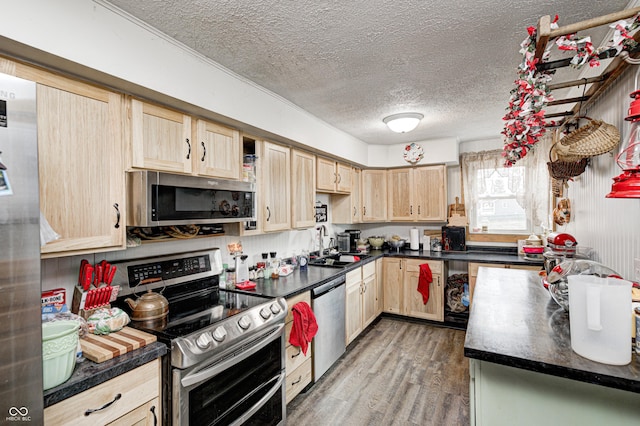 kitchen featuring wood finished floors, appliances with stainless steel finishes, dark countertops, and light brown cabinets