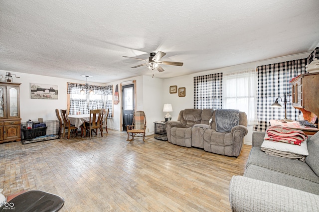 living room featuring ceiling fan, light wood-style flooring, and a textured ceiling