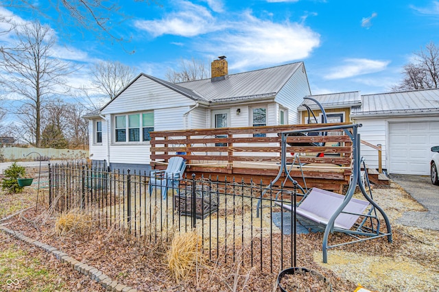 rear view of house with a chimney, fence, metal roof, and a wooden deck