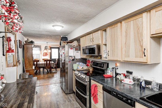 kitchen featuring dark countertops, light brown cabinets, stainless steel appliances, and wood finished floors