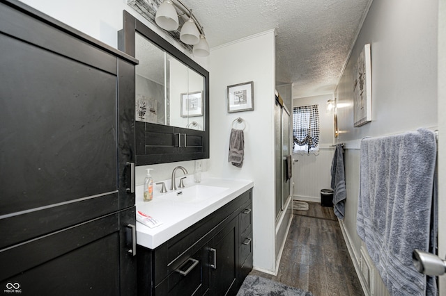 full bath featuring a stall shower, a textured ceiling, vanity, and wood finished floors