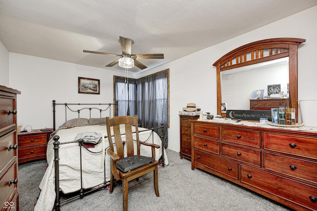 bedroom with a ceiling fan, light colored carpet, and a textured ceiling