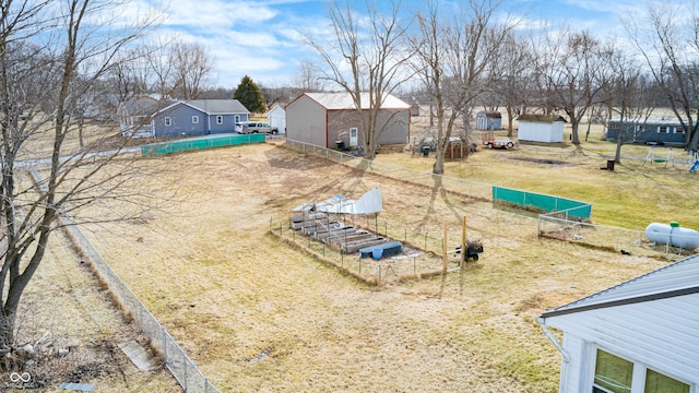 view of yard with a vegetable garden, a residential view, fence, and an outdoor structure