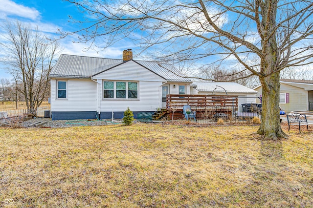 rear view of house featuring a yard, a chimney, metal roof, cooling unit, and a wooden deck