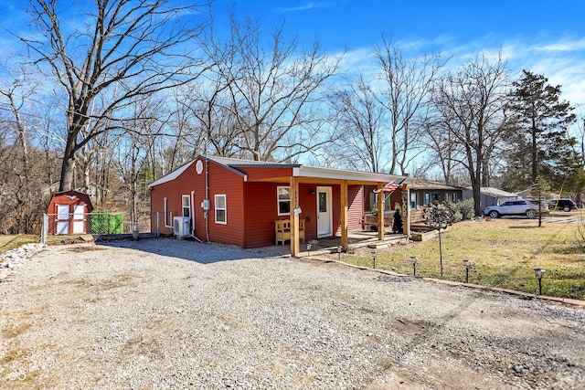 view of front of property featuring an outbuilding, covered porch, fence, a shed, and driveway