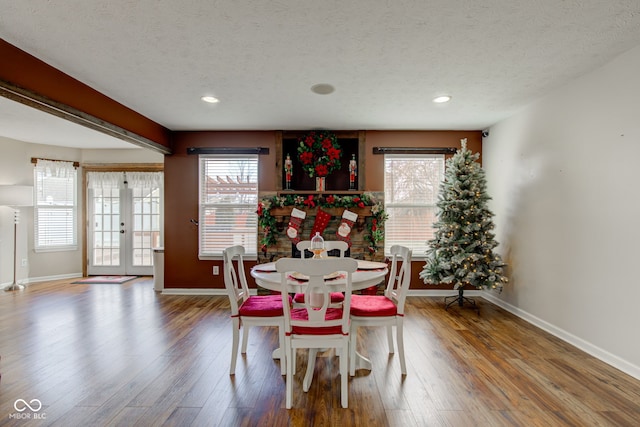 dining space with a textured ceiling, recessed lighting, wood finished floors, baseboards, and french doors