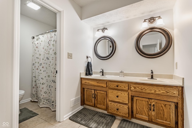 bathroom featuring a sink, visible vents, double vanity, and tile patterned floors