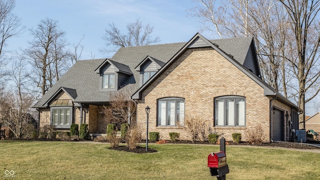 french country inspired facade with a front lawn, an attached garage, brick siding, and a shingled roof