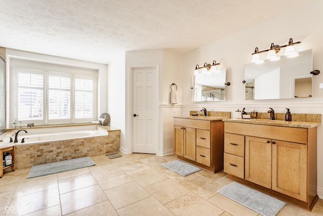 full bath with double vanity, a sink, tile patterned flooring, a textured ceiling, and a bath