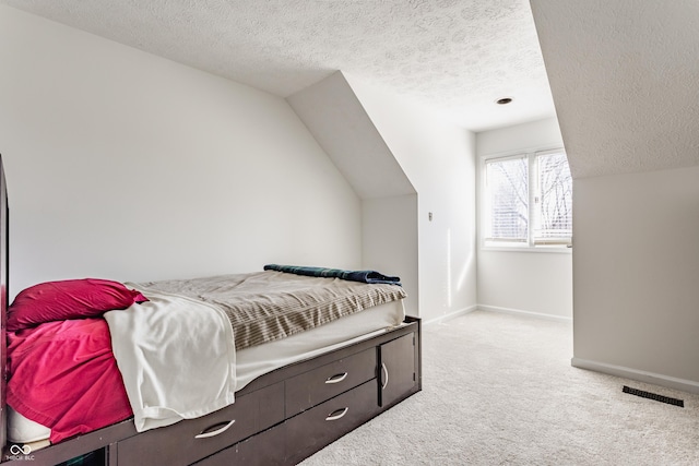 bedroom with visible vents, baseboards, lofted ceiling, carpet flooring, and a textured ceiling