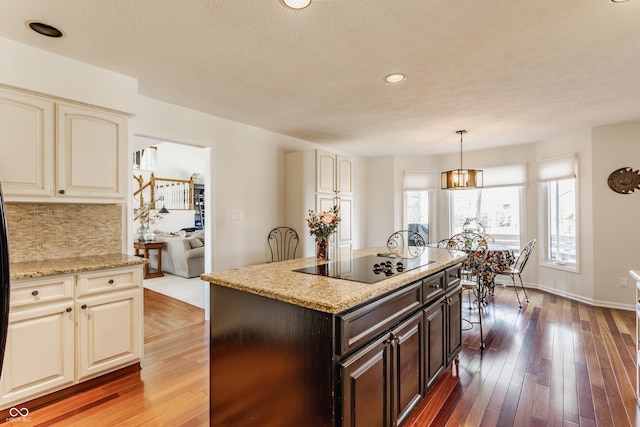 kitchen with black electric cooktop, cream cabinets, hardwood / wood-style floors, and decorative backsplash