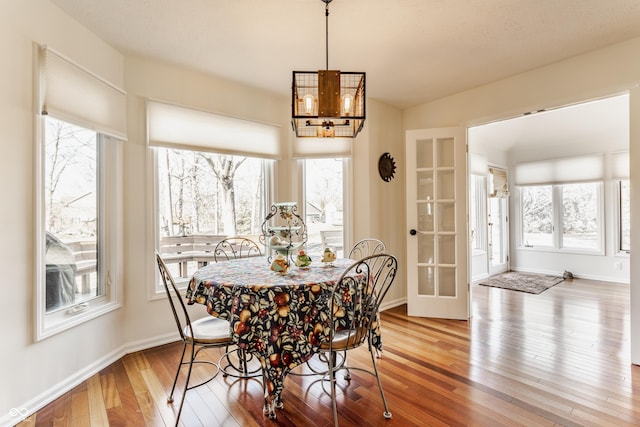 dining room with baseboards, an inviting chandelier, and hardwood / wood-style floors