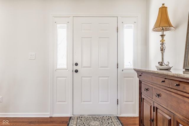 foyer featuring baseboards and dark wood finished floors